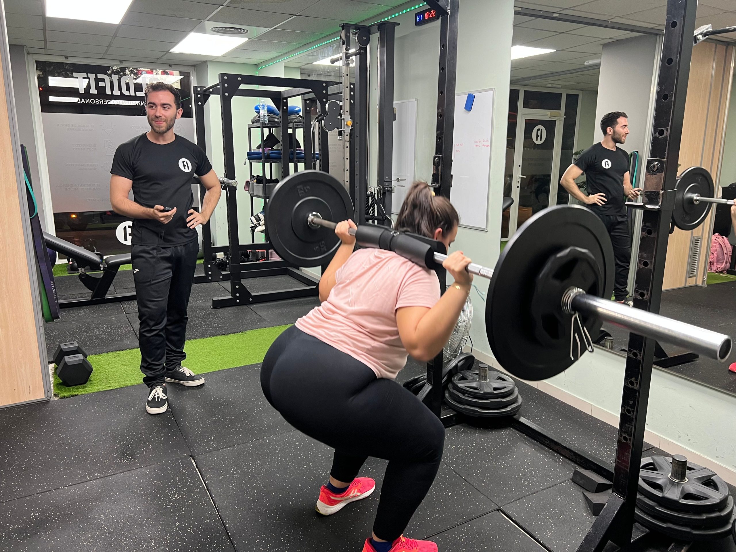 Entrenador acompañando una sentadilla con barra en ALDIFIT